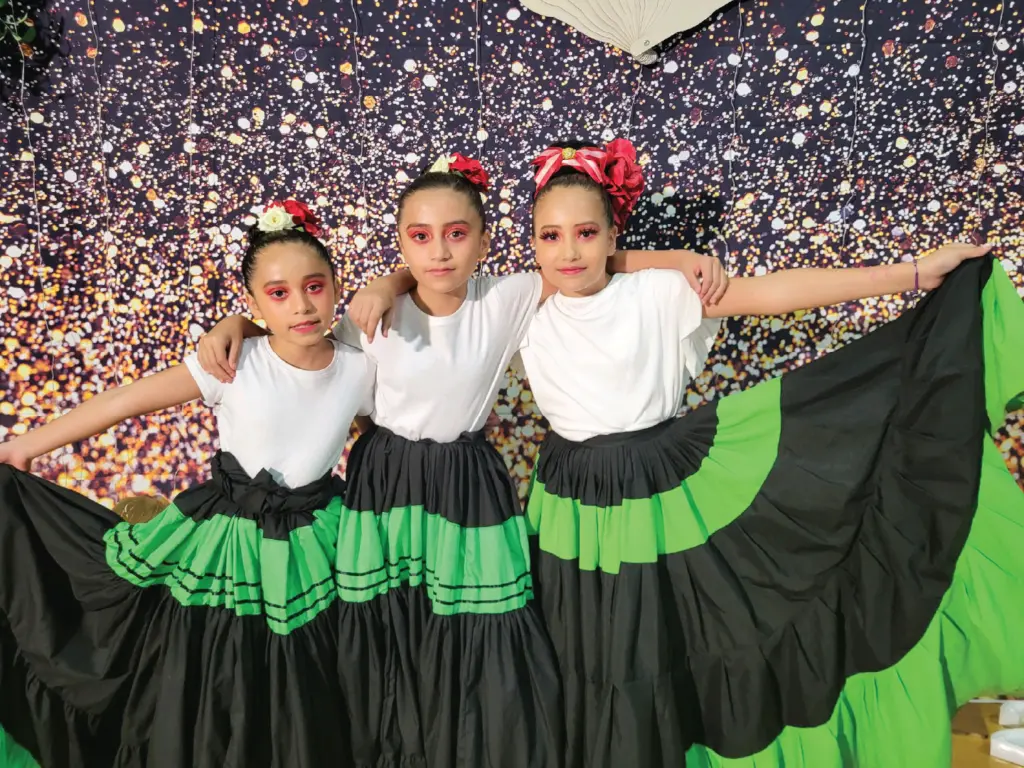 Youth impact folklore dance three girls in black and green dresses.